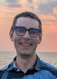Headshot of a man smiling at sunset